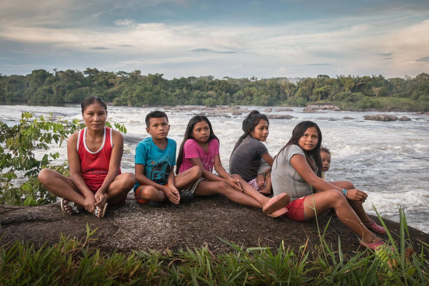 Integrantes de uma comunidade parceira da Saving The Amazon reunidos à beira de um rio, em um dos territórios de restauração