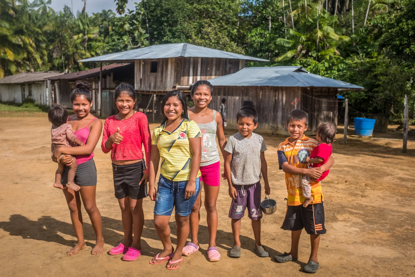 Crianças e jovens de uma comunidade parceira da Saving The Amazon posando em frente às suas casas