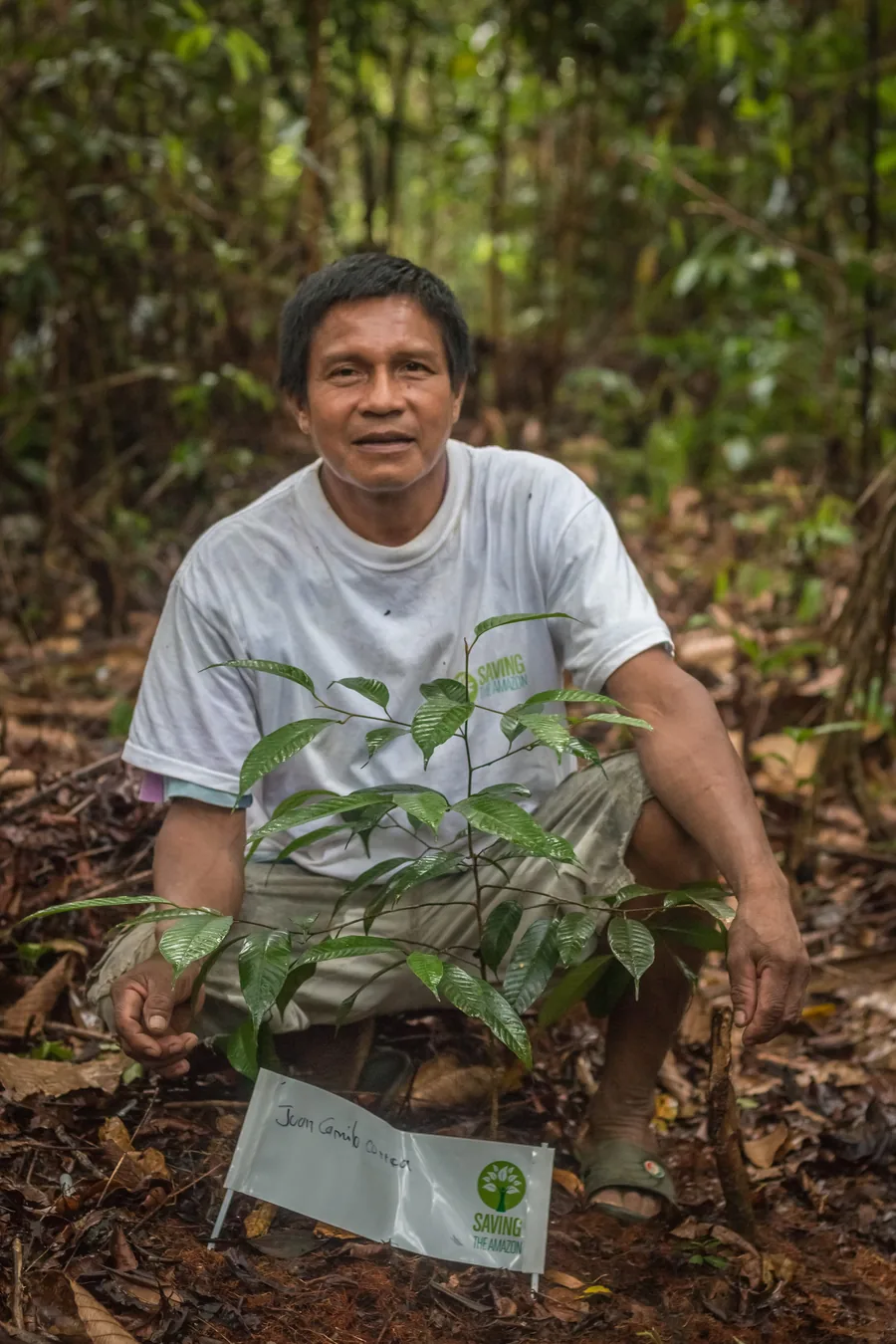 Integrante de uma comunidade parceira da Saving The Amazon ao lado da árvore que plantou, identificada com seu nome